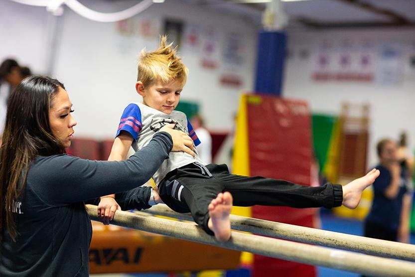 boy in straddle hold on parallel bars