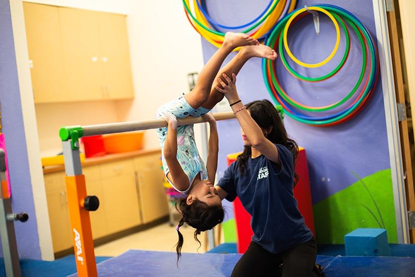 girl doing a pullover on bars